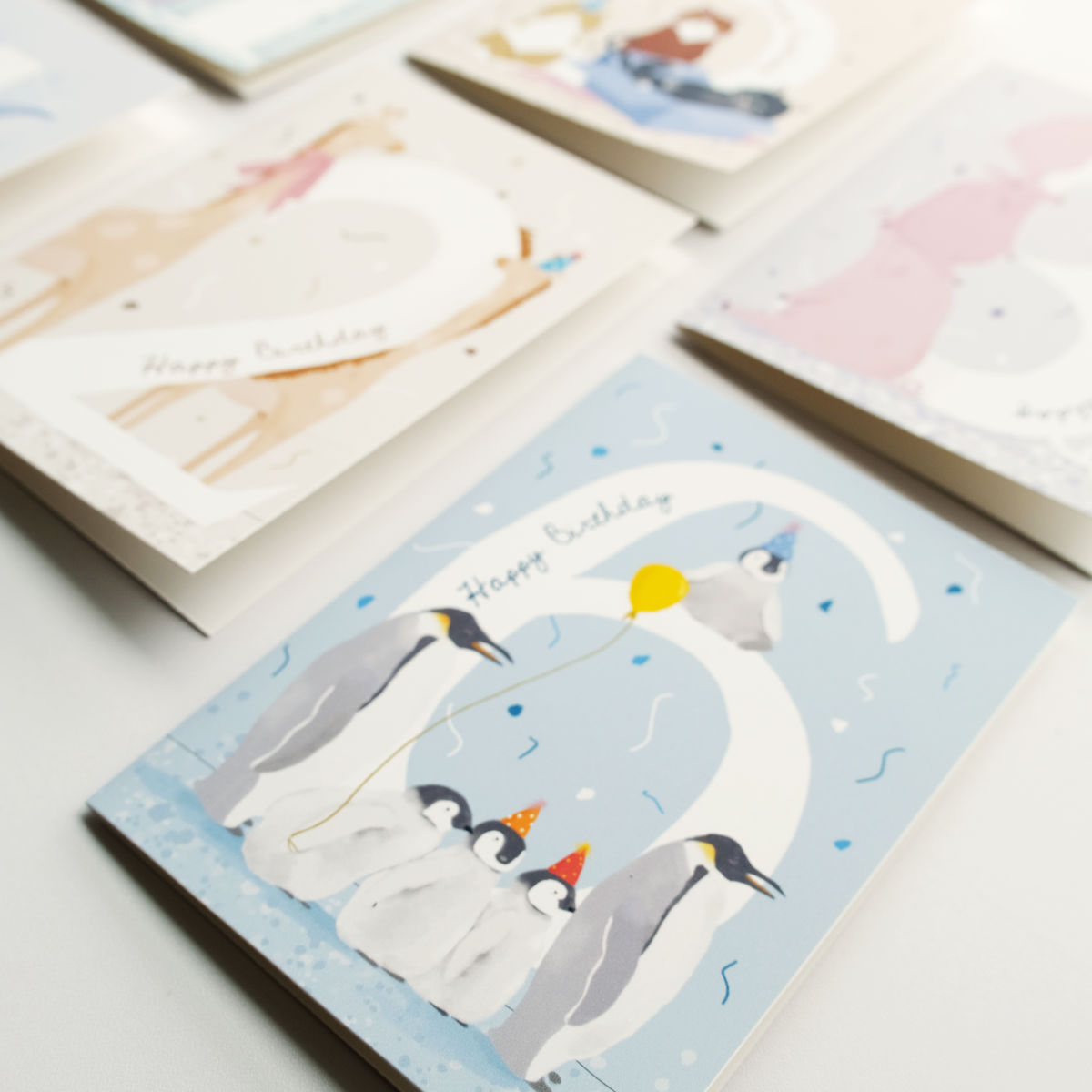 Greeting card with penguins and number 6 and the word "Happy Birthday", brown  envelope on a white background