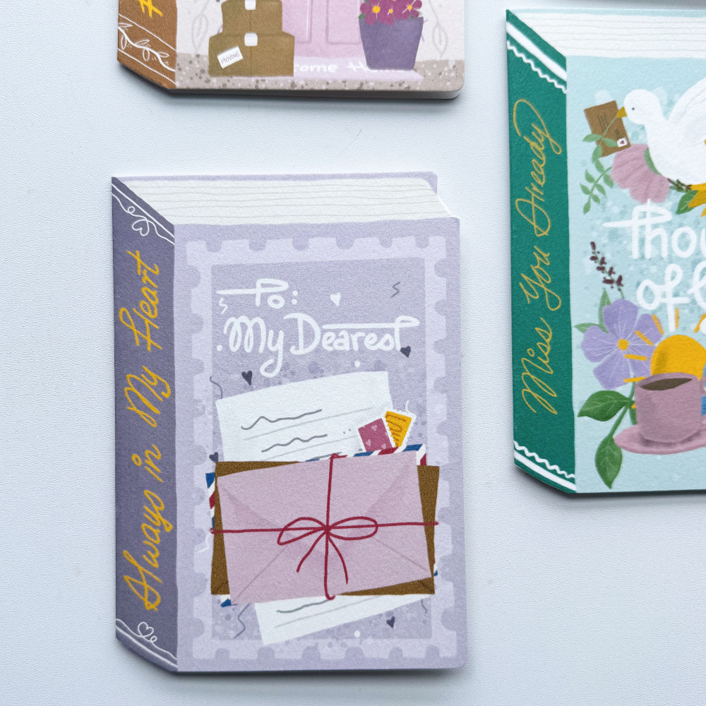 A decorative book-shaped greeting card or stationery item titled "To My Dearest" with illustrated letters and an envelope on the front, shown on a white background. Part of another matching card is visible at the top and a third colorful card at the right edge.